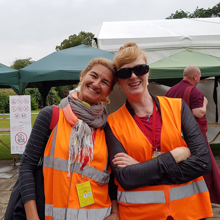 Two women with hi visibility vests helping at Festival