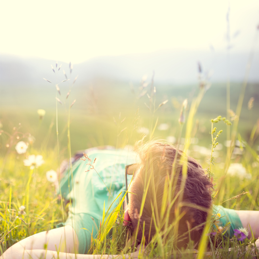 Young man lying on back in field, enjoying life