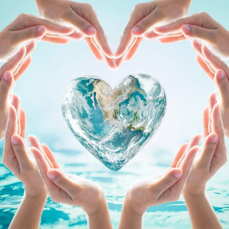 Hands in heart shape around planet earth