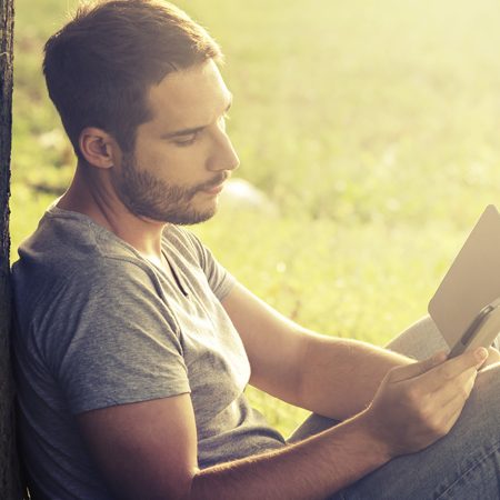 Thoughtful man reading under tree