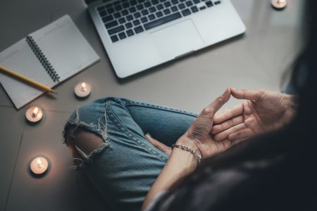 Person meditating at computer, with candles