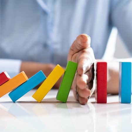 Woman stopping brightly coloured dominoes from falling over