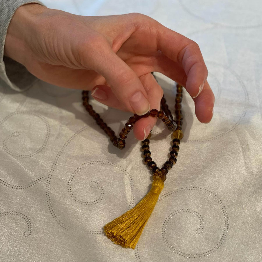 A hand counting mantras on a Mala
