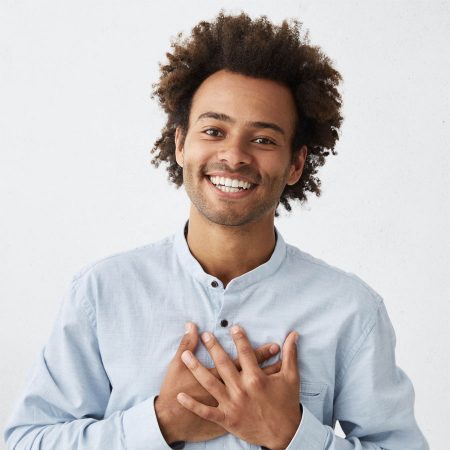 Young African American man, smiling, with hands over heart