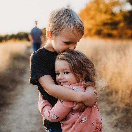 Little boy & girl hugging, happy on country trail