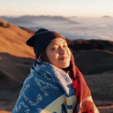 Happy woman meditating, outdoors with blanket wrapped around herself