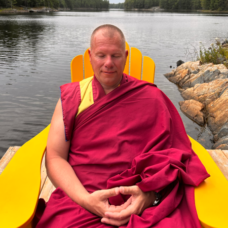 Buddhist monk Gen Thekchen meditating by lake.